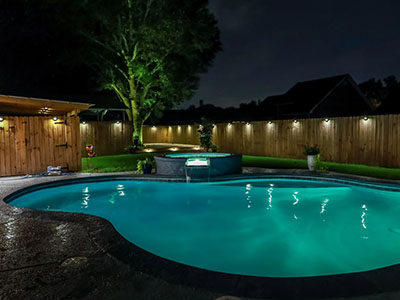 A backyard swimming pool and jacuzzi hot tob at night